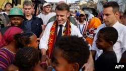 French President Emmanuel Macron speaks to children during his visit to the Kawani district of Mamoudzou in the French Indian Ocean territory of Mayotte, following the passage of Cyclone Chido over the archipelago on December 19, 2024.