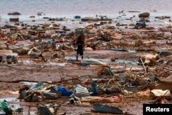 A boy carries roofing sheets on the beach after Cyclone Chido in Pesamenti, Mayotte, on December 20, 2024.