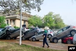 Residents walk past cars stuck in flood waters in eastern Spain on October 30, 2024.