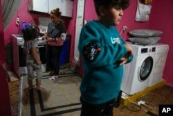 Rukiye Sahin, 28, talks to her 5-year-old daughter Dilan, near her 11-year-old son Atakan in the family's one-room apartment in the Tarlabaği neighborhood of Istanbul, Turkey, on December 4, 2024.