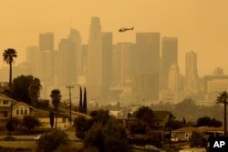 The sky is filled with smoke from multiple wildfires surrounding the Los Angeles skyline on January 9, 2025.