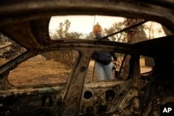 Lisa Renn looks at the remains of a car in Altadena, California on January 9, 2025.