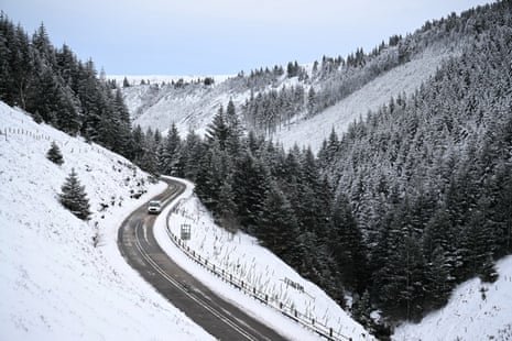 A man drives a car through a snow-covered landscape on Snake Pass Road in the Peak District on Wednesday.